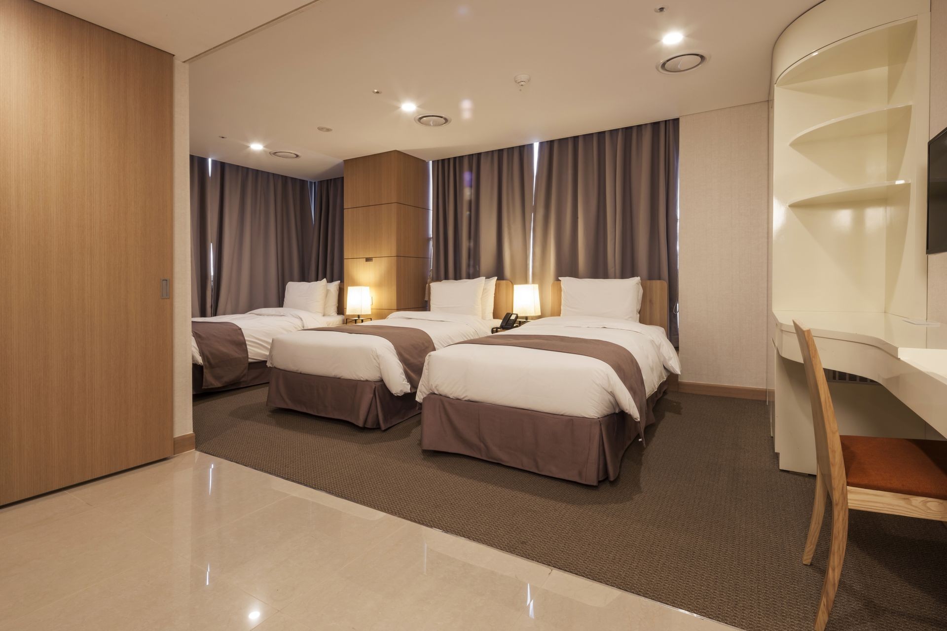 A business hotel room with triple bed, curtain, table, chair, blanket, window in seoul, korea.